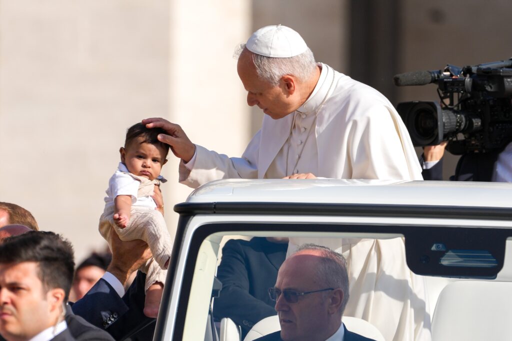Pope Leo XIV greets a child from the popemobile as he rides around St. Peter's Square at the Vatican before his weekly general audience, September 17, 2025.