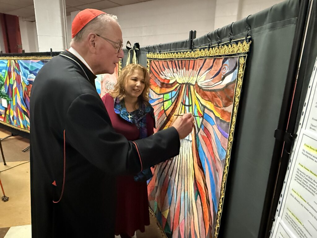 Cardinal Timothy Dolan (foreground) paints the final trapezoid of a mural created by the Holy Rosary Church community, and led by Yvette Armstrong (right), October 5, 2025.