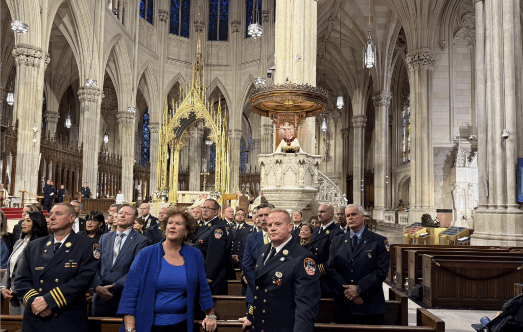 Attendees at the Guardian Mass turn to look at the new mural honoring law enforcement, firefighters, and fire responders at the entrance to St. Patrick’s Cathedral, as Cardinal Timothy Dolan (on pulpit) offers his homily, October 2, 2025.