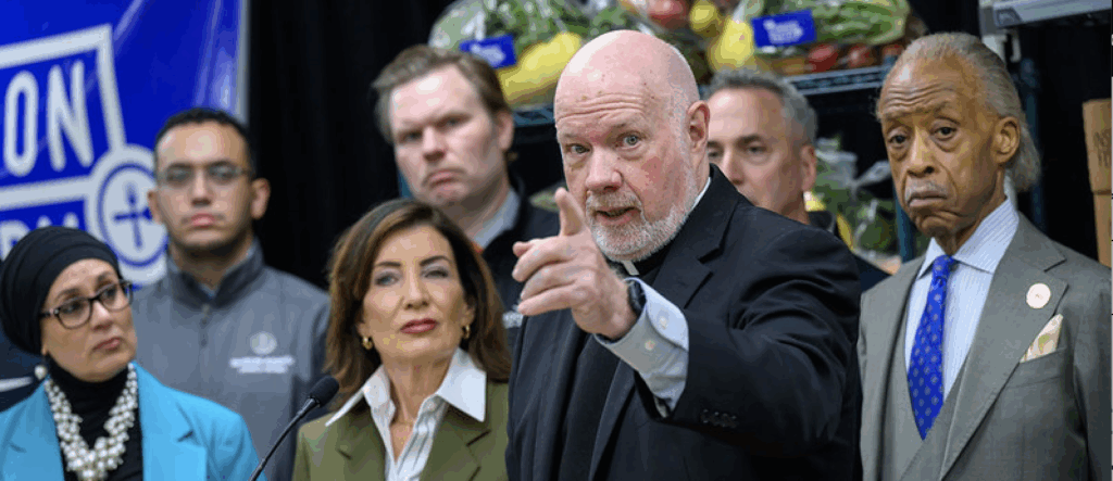 Monsignor Kevin Sullivan (center) announces Catholic Charities of New York's response to the upcoming suspension of SNAP benefits, at a press conference held by Governor Kathy Hochul (center left) as she declared a state of emergency to address the situation.