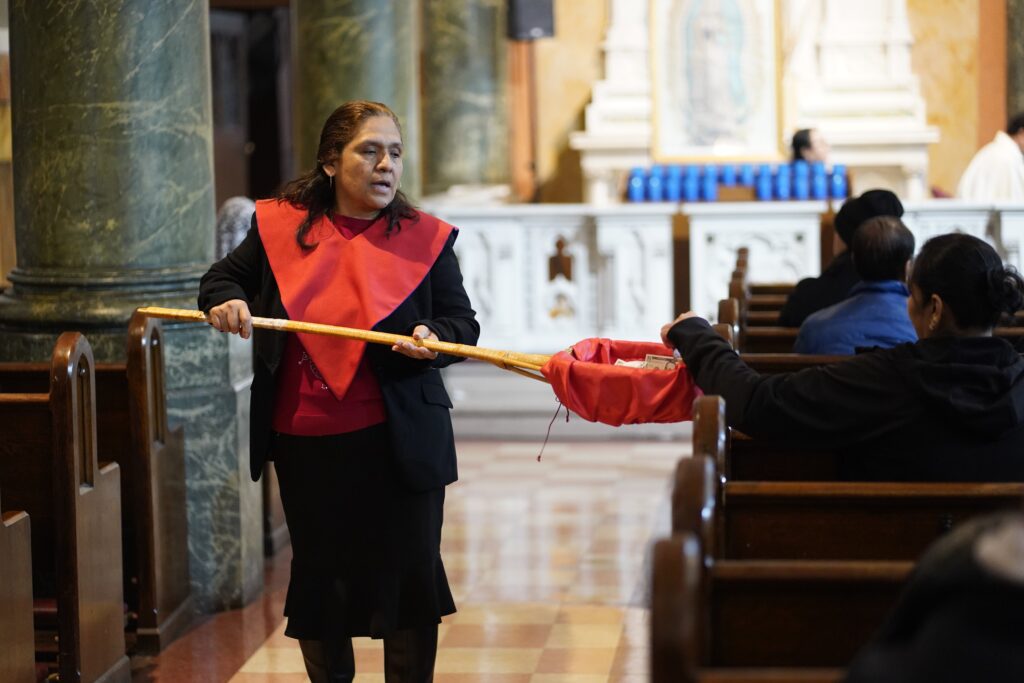 An usher takes up a collection during Mass at St. Rose of Lima Church in the Kensington section of Brooklyn, April 7, 2025.