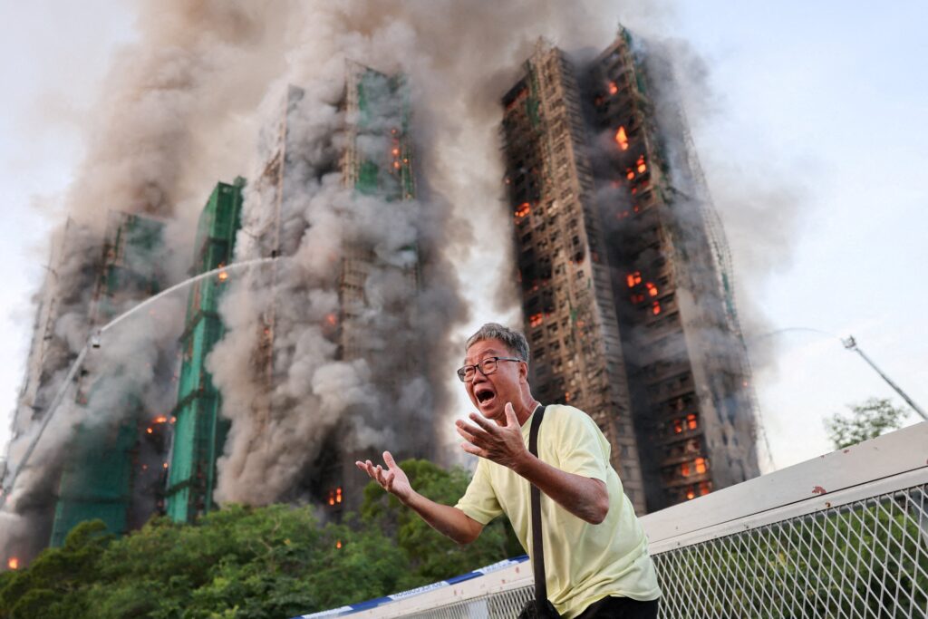 A 71-year-old man reacts after claiming his wife is trapped inside Wang Fuk Court apartment complex during a major fire in the Tai Po district of Hong Kong on November 26, 2025.