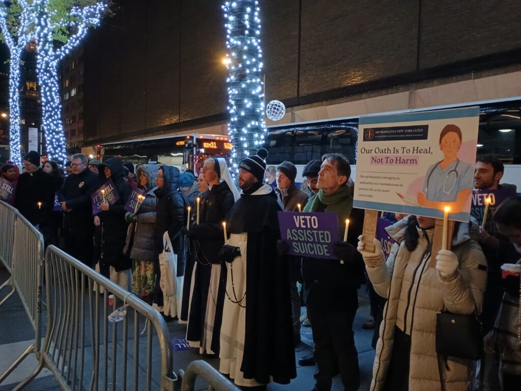 Auxiliary Bishop Peter Byrne of the Archdiocese of New York (far left) joins several dozen people, including Sisters of Life, for the candlelight vigil outside Governor Hochul’s Manhattan office on December 4, 2025. Photo: Armando Machado/The Good Newsroom