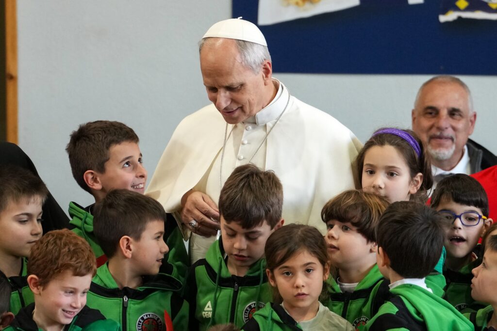 Pope Leo XIV chats with children before posing for a group photo during his pastoral visit to the Parish of Santa Maria Regina Pacis in Ostia Lido, Italy, February 15, 2026.