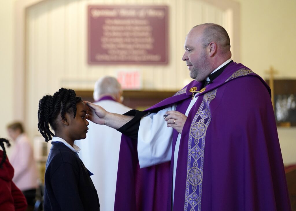 Father Sean Suckiel, pastor of Holy Family Church in Fresh Meadows,, imposes ashes on second-grader Mia Simons of Holy Family Catholic Academy during an Ash Wednesday prayer service February 14, 2024. Photo: OSV News photo/Gregory A. Shemitz
