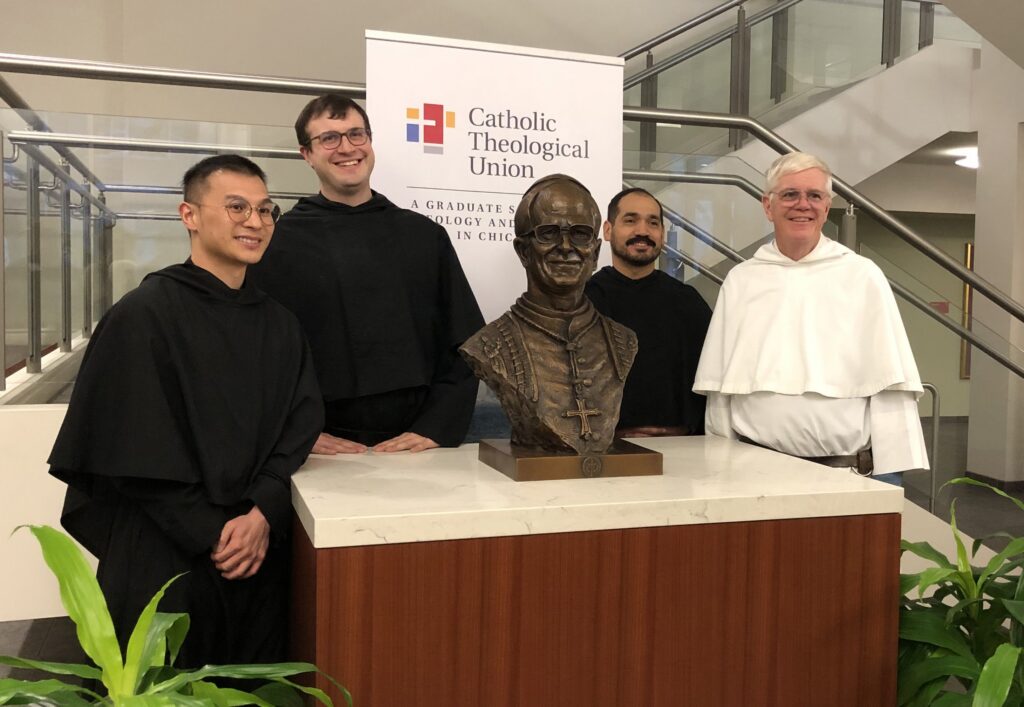 Augustinian Father John Lydon, right, and three Augustinian seminarians pose with the newly unveiled bronze bust of Pope Leo XIV at the bottom of the staircase of Catholic Theological Union in Chicago February 22, 2026.