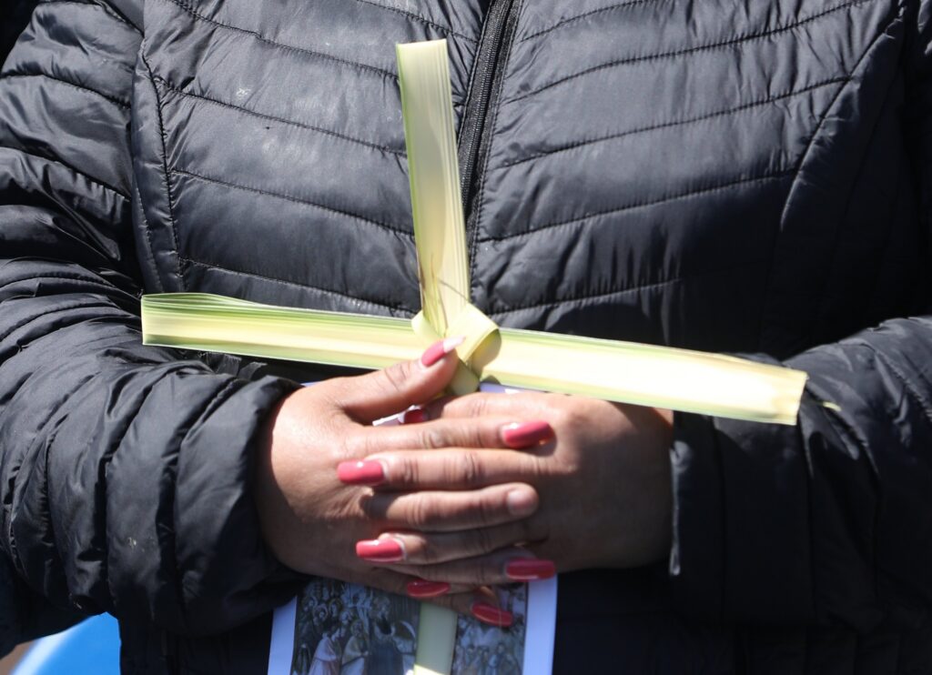 A woman holds a palm frond cross during Palm Sunday Mass outside St. Mary's Chapel at the National Shrine Grotto of Our Lady of Lourdes in Emmitsburg, Maryland, April 2, 2023.