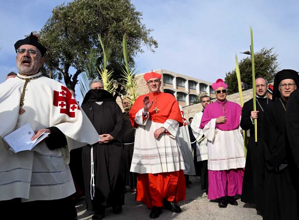 Cardinal Pierbattista Pizzaballa, Latin patriarch of Jerusalem, waves as he walks the traditional path that Jesus took on his last entry into Jerusalem during the Palm Sunday procession on the Mount of Olives in Jerusalem April 2, 2023. Photo: OSV News/Debbie Hill