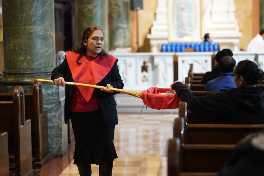 An usher takes up a collection during Mass at St. Rose of Lima Church in the Kensington section of Brooklyn, April 7, 2025.