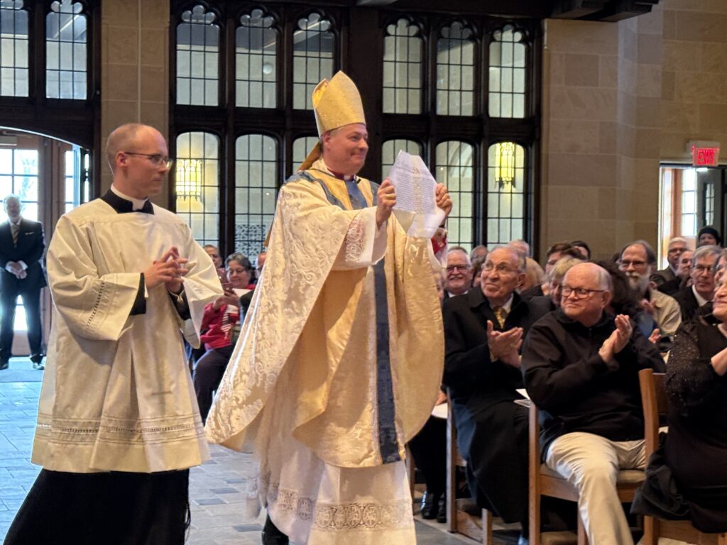 Bishop John S. Bonnici (holding scroll) displays the papal bull of appointment naming him as the 10 th Bishop of Rochester, March 20, 2026, at the Cat hedral of the Sacred Heart in Rochester.