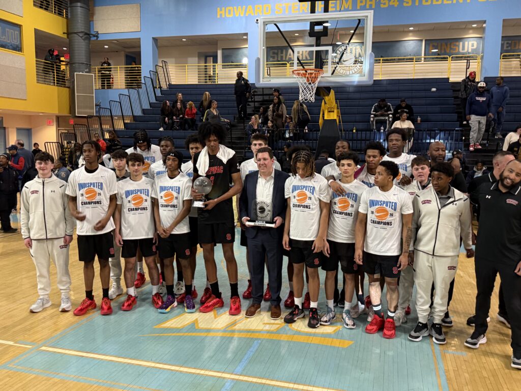 Archbishop Stepinac High School Head Basketball Coach Patrick Massaroni (center, with trophy) stands with members of the "AA" varsity team, winners of the 2026 "Undisputed Championship" between Catholic and public high school champions, March 22, 2026.