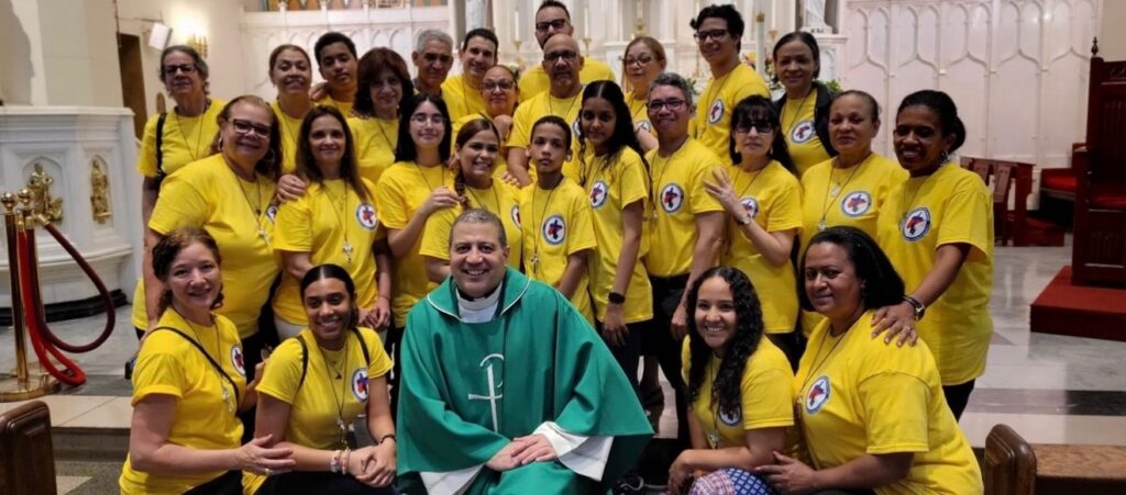 Faithful volunteers of St. Elizabeth Church, Washington Heights area of Manhattan, gathered around the pastor, Father Ambiorix Rodriguez, in a 2025 group photo inside the church.