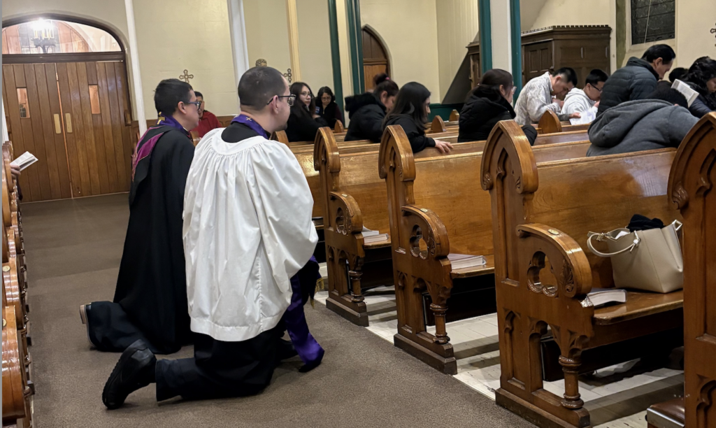 Father Arthur Rojas (left) and Father Arlady Rosado genuflect with the people during the Stations of the Cross.