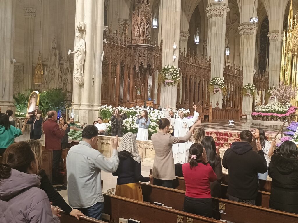 Father Vincent Druding and choir members lead the faithful in praise and worship music during a brief revival that preceded the evening. Young Adult Mass at St. Patrick's Cathedral, Wednesday, April 8, 2026. Photo by: Armando Machado/The Good Newsroom