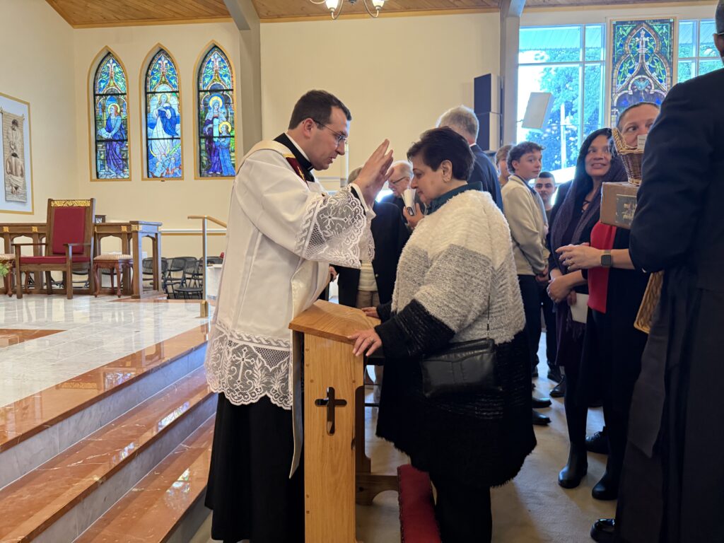 Father Joe Haas (left) offer his first blessing to a parishioner of the Church of St. Mary in Washingtonville, his home parish and where he was first asked by Cardinal Timothy Dolan if he had ever considered the priesthood.