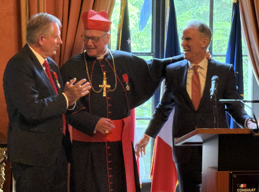 Ambassador of France to the United States Laurent Bili (left) shares a light moment with Cardinal Timothy Dolan (center) and Chancellor of the Archdiocese of New York John Cahill on Tuesday, May 26, 2026, at a ceremony at the Consulate General of France in Manhattan. Cardinal Dolan received the Legion of Honour (Ordre national de la Légion d'honneur) of France in recognition of his leadership of fundraising efforts to restore Notre-Dame Cathedral in Paris after it was damaged by fire in 2019.