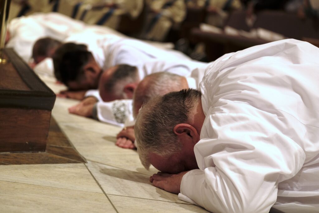 Men lie prostrate during their ordination to the diaconate at the Catholic Pastoral Center in Nashville, Tenn., April 1, 2023. Bishop J. Mark Spalding of Nashville ordained 12 permanent deacons and one transitional deacon.