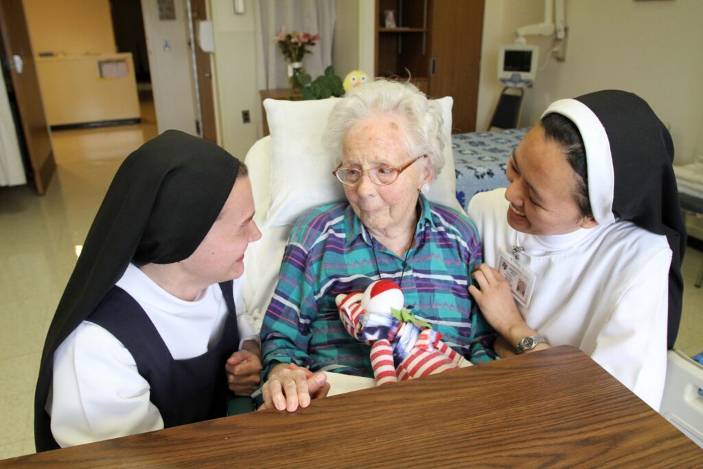 A file photo shows Dominican postulant Anna Harper, a native of Baton Rouge, La., and Dominican Sister Carmela Marie, a native of Hinatuan, Philippines, visit with patient Edna MacCready at Rosary Hill Home in Hawthorne.