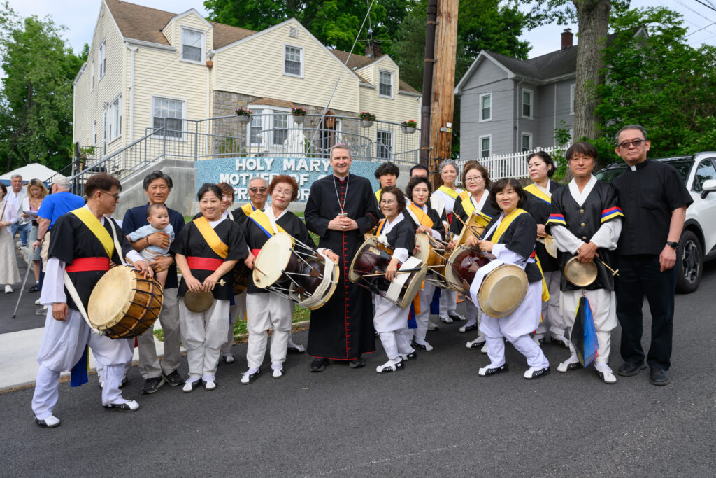 Archbishop Ronald Hicks (center) and Hartsdale's Sacred Heart Church Pastor Fr. Michael Moon (right) pose with members of a pungmul, a traditional Korean drum group, that performed for the 100th anniversary of the church on June 14, 2026.