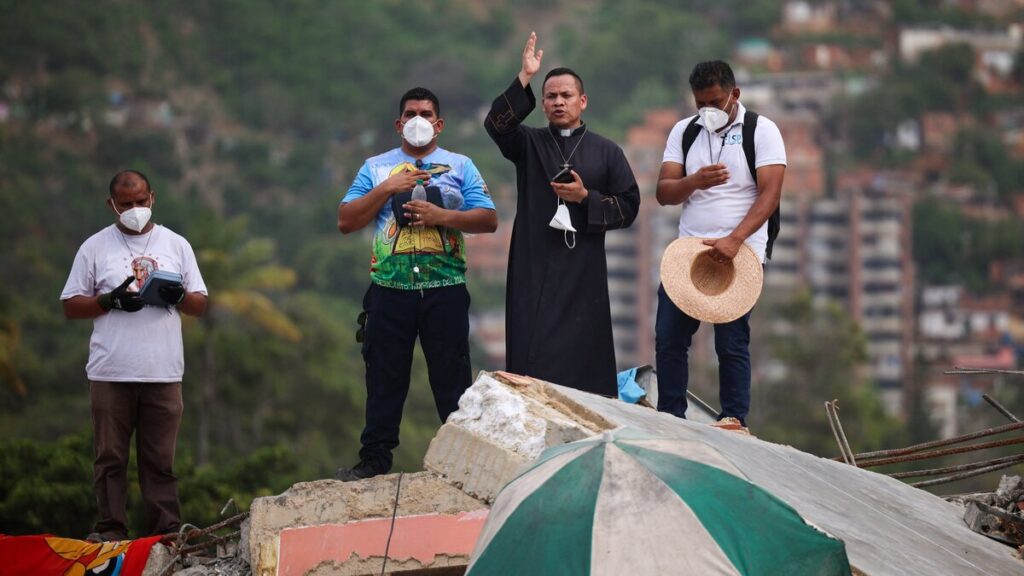 Un sacerdote imparte una bendición mientras se encuentra de pie entre los escombros en el lugar donde se derrumbó un edificio en La Guaira, Venezuela, el 1 de julio de 2026, tras los terremotos. (Foto de OSV News/Adriano Machado, Reuters)