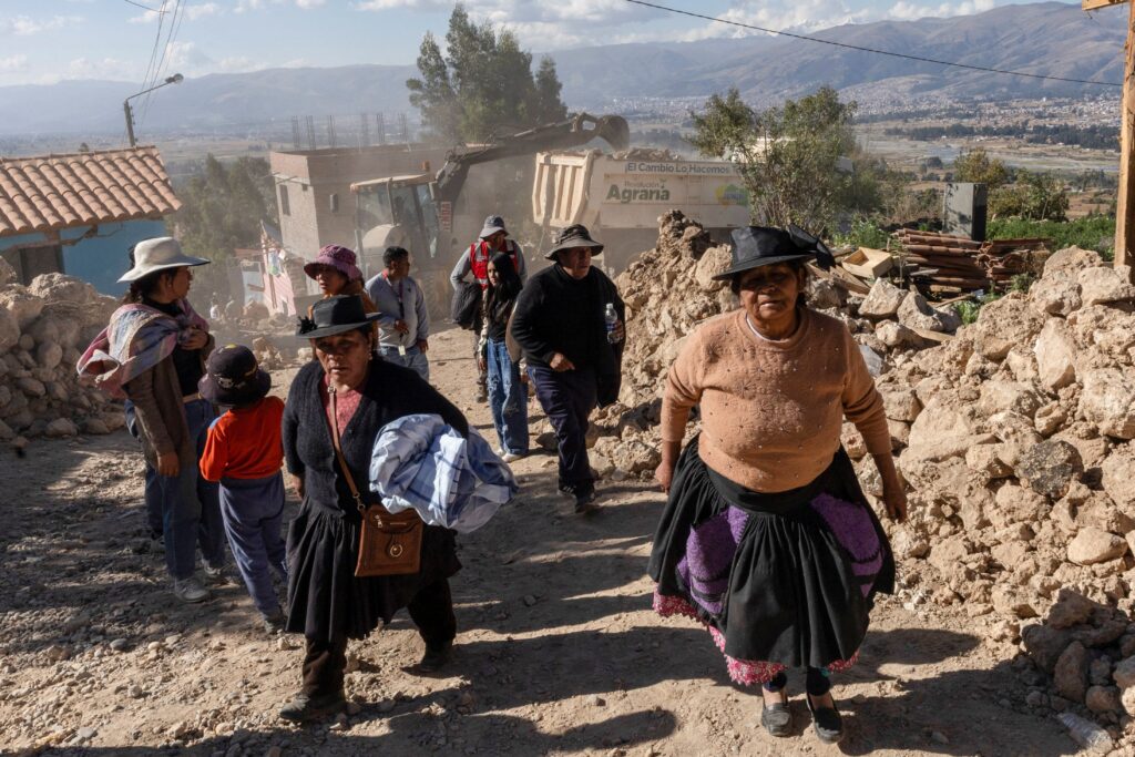 People walk past destroyed homes in Junín, Peru, July 19, 2026, following the magnitude 5.1 earthquake that struck Central Peru.