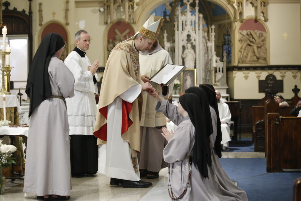 Archbishop Ronald Hicks celebrated the Perpetual Profession Mass for the Franciscan Sisters of the Renewal on June 6 and is pictured here placing the ring on the finger of the newly professed, symbolizing her spousal relationship with Christ.  The Sisters are joyfully pictured here after the Mass: Sr. Mae Quentin, 35, from Wisconsin; Sr. Rosa Montano, 29, from New Jersey; Sr. Emmanuel Schulte, 34, from South Dakota.