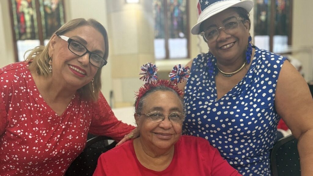 Miembros del centro STAR Older Adults Center posan sonriendo en la Iglesia de Santa Isabel, en Washington Heights. (De izquierda a derecha): las señoras Torres, Arias y Ramírez en julio de 2026. Foto cortesía de Stephany Cruz.
