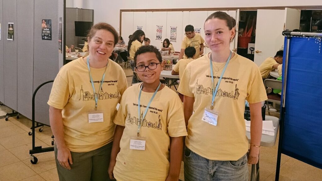 Ana Paula Panzarini, directora de Evangelización y Formación en la Fe de la parroquia del Santo Nombre de Jesús/San Gregorio Magno (Manhattan), con Sterling Luna, de 10 años, y Johanna S. Rueddel, de 16 años, durante el campamento de verano para adolescentes de la parroquia el jueves 30 de julio de 2026. Foto de Armando Machado/The Good Newsroom.