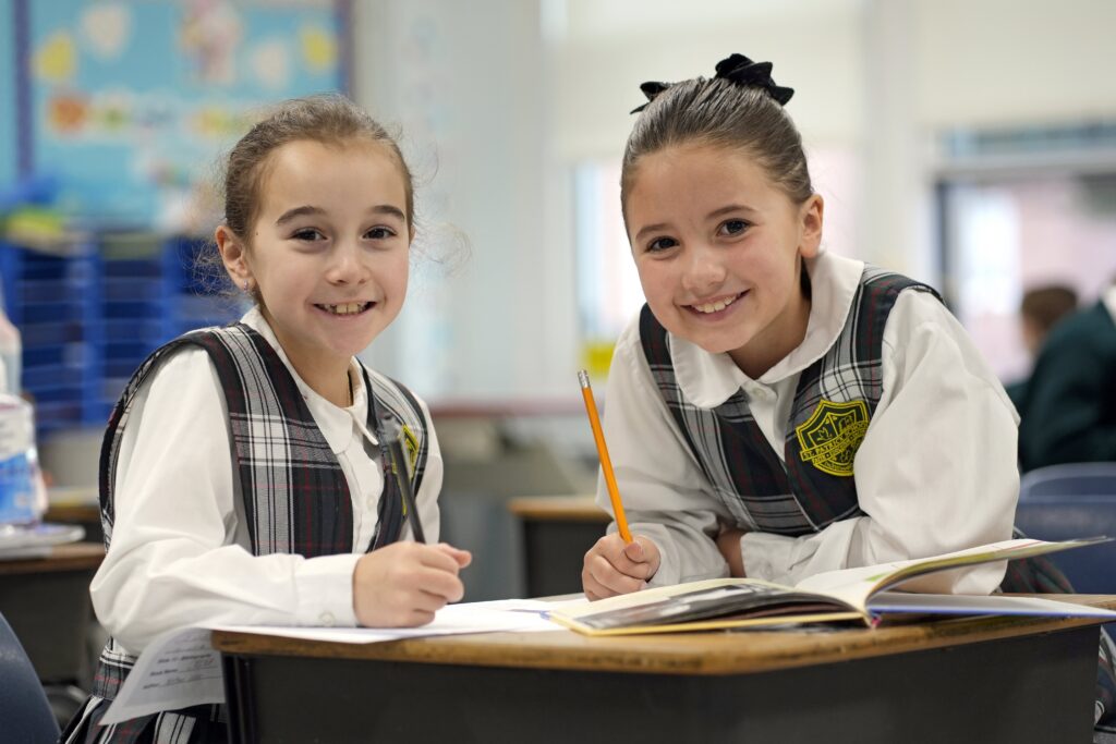 Third-graders Layla Leocata, left, and Payton Pardee pose for a photo while working on a geography assignment during class at St. Patrick School in Smithtown, Jan. 15, 2026.