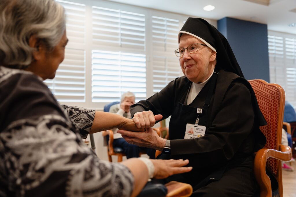 A Carmelite sister cares for a resident at Ozanam Hall in the Bayside neighborhood of the New York borough of Queens. On July 30, 2026, a judge temporarily shielded four orders of women religious and Catholic healthcare ministries from enforcement of a New York state law allowing physicians to aid terminally ill adults in dying by suicide.
