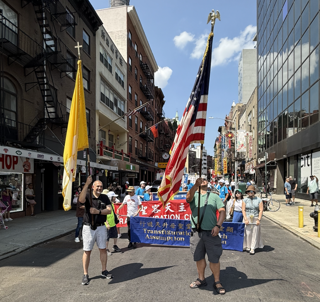 Flag bearers and banner carriers prepare to lead the Church of the Transfiguration's 30th Assumption procession on Sunday, August 9, 2026.
