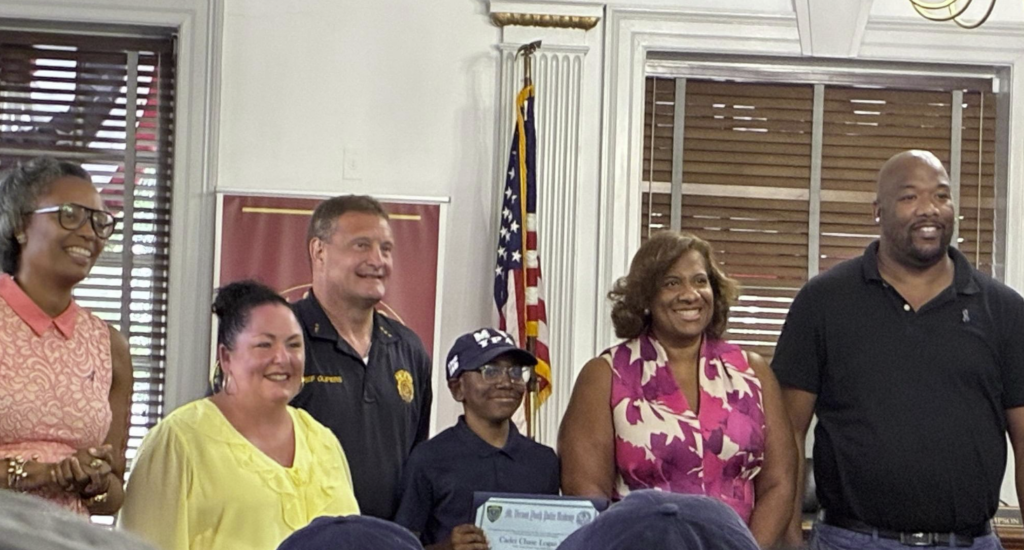 Our Lady of Victory incoming sixth-grader Chase Reid (middle) receives his certificate from the Mount Vernon Police Department after completing its Youth Police Academy in August 2026.