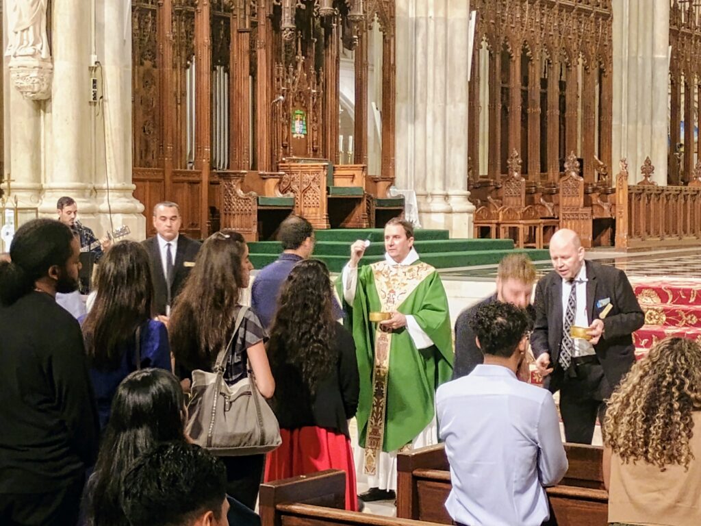 Fr. Cassian Derbes, O.P., (center) of the Dominican Friars, distributes communion during the August Young Adult Mass at St. Patrick's Cathedral on Wed., Aug. 5.