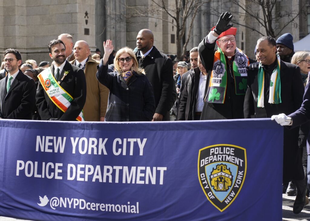Cardinal Timothy M. Dolan (second right), Archbishop Emeritus of New York, waves as he marches with New York Police Commissioner Jessica Tisch (center, waving) and New York Mayor Zohran Mamdani in the 265th St. Patrick's Day Parade in Manhattan on March 17, 2026. Cardinal Dolan and Commissioner Tisch will both be honored at this year's annual Al Smith Dinner, to be held on October 15, 2026.