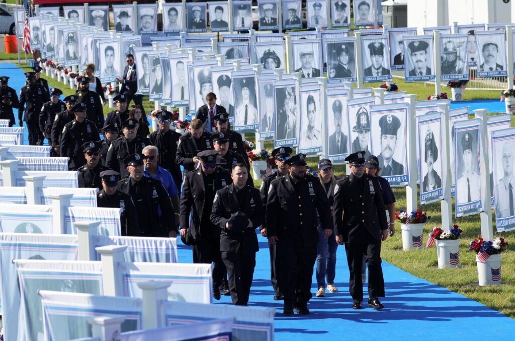 Police officers walk past photographs of victims who died in the 9/11 terrorist attacks ahead of the "Steel Across America" event on the Ellipse near the White House in Washington Sept. 8, 2026. Photo: OSV News/Nathan Howard, Reuters