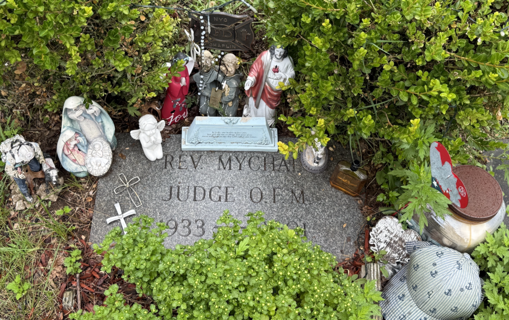 The grave of Fr Mychal Judge, Franciscan friar and FDNY chaplain, is decorated with figurines and items of faith at Holy Sepulchre Cemetery in Totowa, N.J., photographed on Sept. 1, 2026.