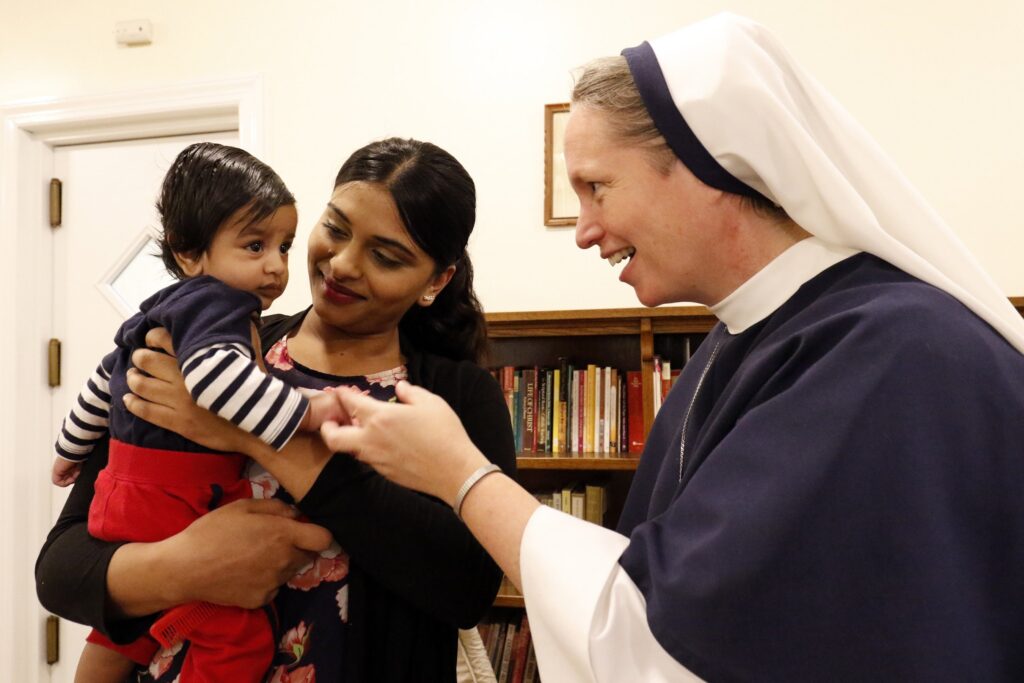 Rohini Brijlall is pictured in a file photo holding her three-month-old son Zakarya as Sister Mary Elizabeth, then vicar general of the Sisters of Life, talks with the child at the religious community's Holy Respite residence in the Hell's Kitchen neighborhood of Manhattan.