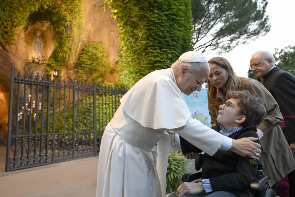 Pope Leo XIV greets a disabled child after joining hundreds of children in praying the rosary for peace at the Lourdes Grotto in the Vatican Gardens on the evening of Oct. 1, 2026, the month dedicated to the rosary.