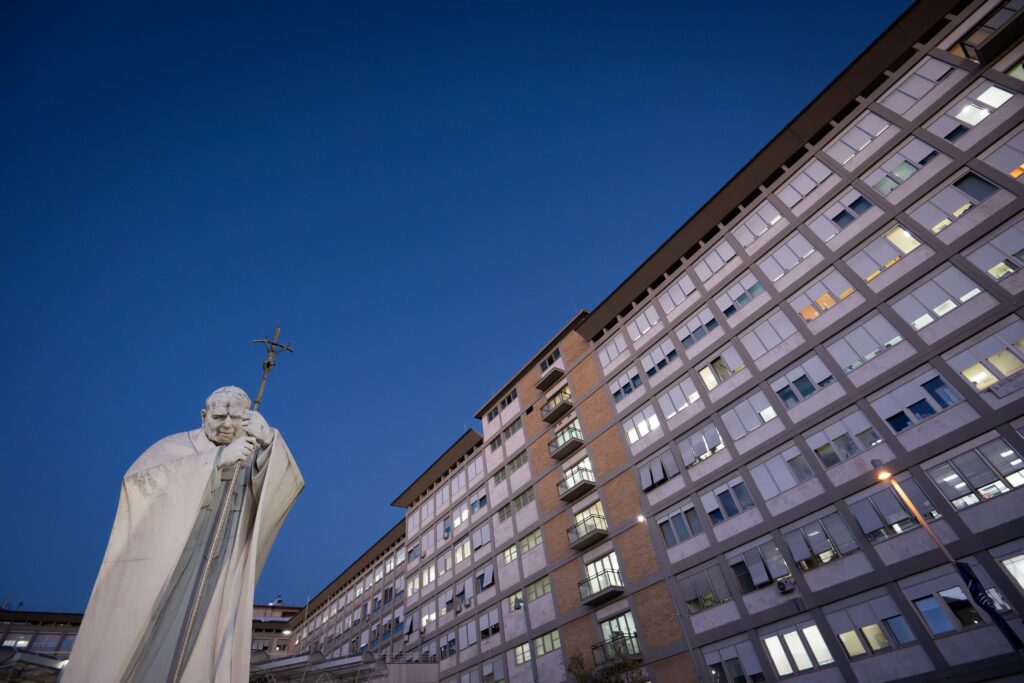 A statue of St. John Paul II can be seen in front of the evening sky outside of Rome's Gemelli hospital where Pope Leo XIV underwent surgery to remove a nodule in his lung Oct. 13, 2026. The Vatican press office said the procedure was a success.