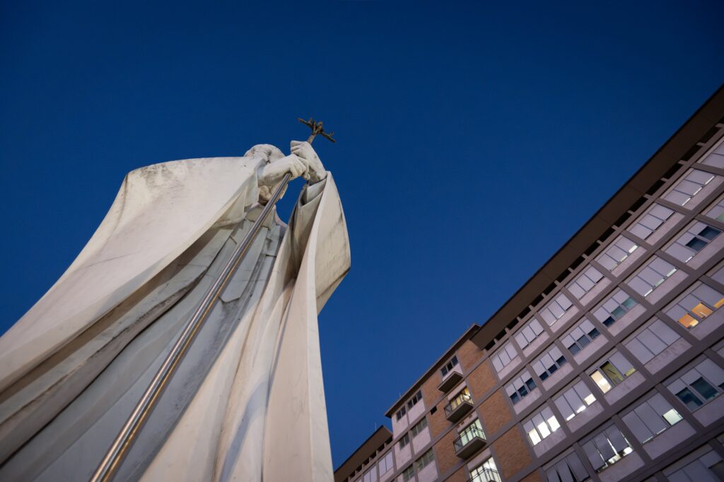 A statue of St. John Paul II can be seen in front of the evening sky outside of Rome's Gemelli hospital where Pope Leo XIV underwent surgery to remove a nodule in his lung Oct. 13, 2026. The Vatican press office said the procedure was a success.