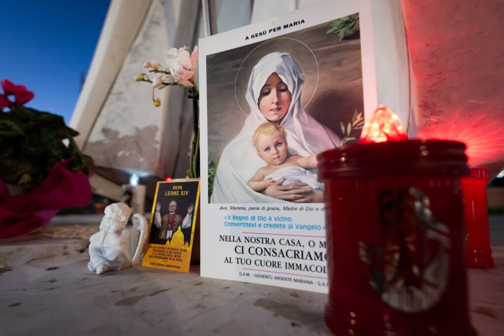 Devotional items can be seen at the foot of a statue of St. John Paul II outside of Rome's Gemelli hospital where Pope Leo XIV underwent surgery to remove a nodule in his lung Oct. 13, 2026. The Vatican press office said the procedure was a success.