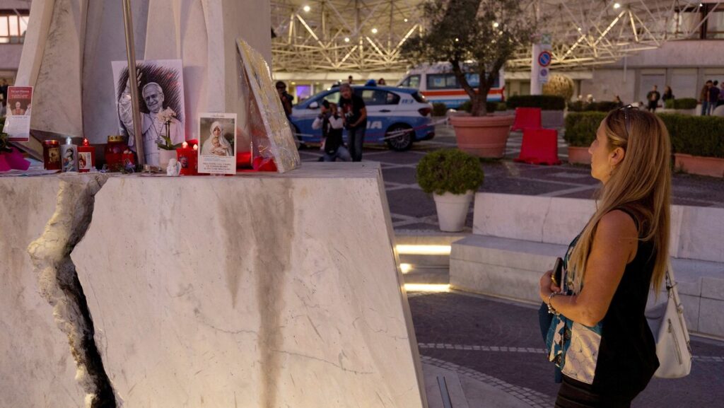 A woman prays at the base of a statue of St. John Paul II outside Rome's Gemelli Hospital Oct. 15, 2026. Doctors treating Pope Leo XIV said Oct. 15 that tests show "good recovery of the operated lung" two days after his cancer surgery. The pope underwent surgery Oct. 13 to remove the lower lobe of his right lung and was diagnosed with lung cancer. (OSV News photo/Remo Casilli, Reuters)