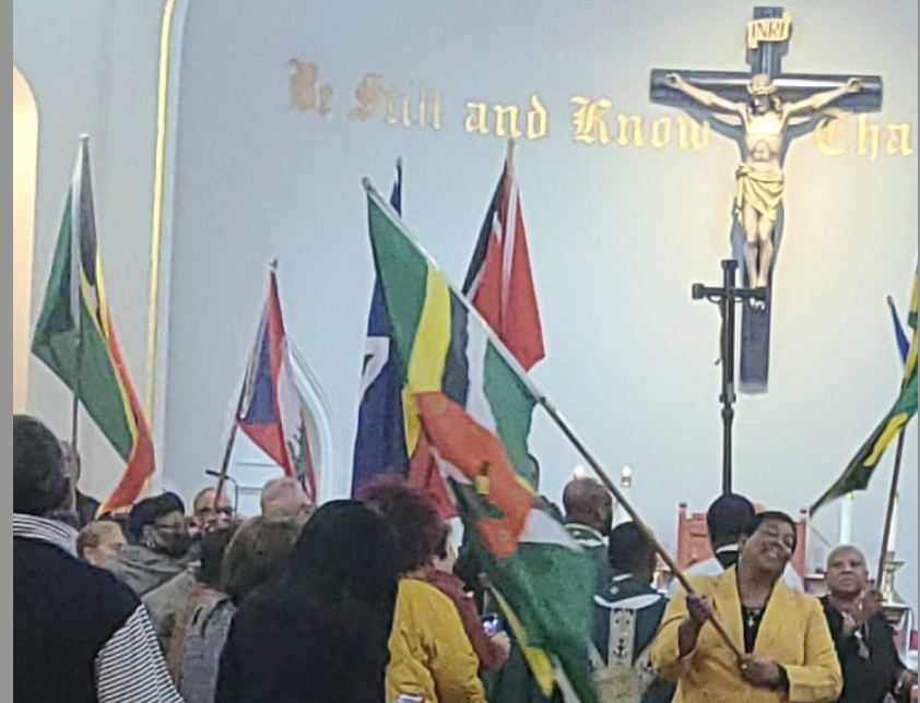 The faithful wave flags of several Caribbean island nations during the 2023 Caribbean Mass at St. Mary/Our Lady of Mt. Carmel Church in Mount Vernon.