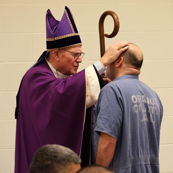 Cardinal Dolan gives a blessing after Mass to one of the prisoners.