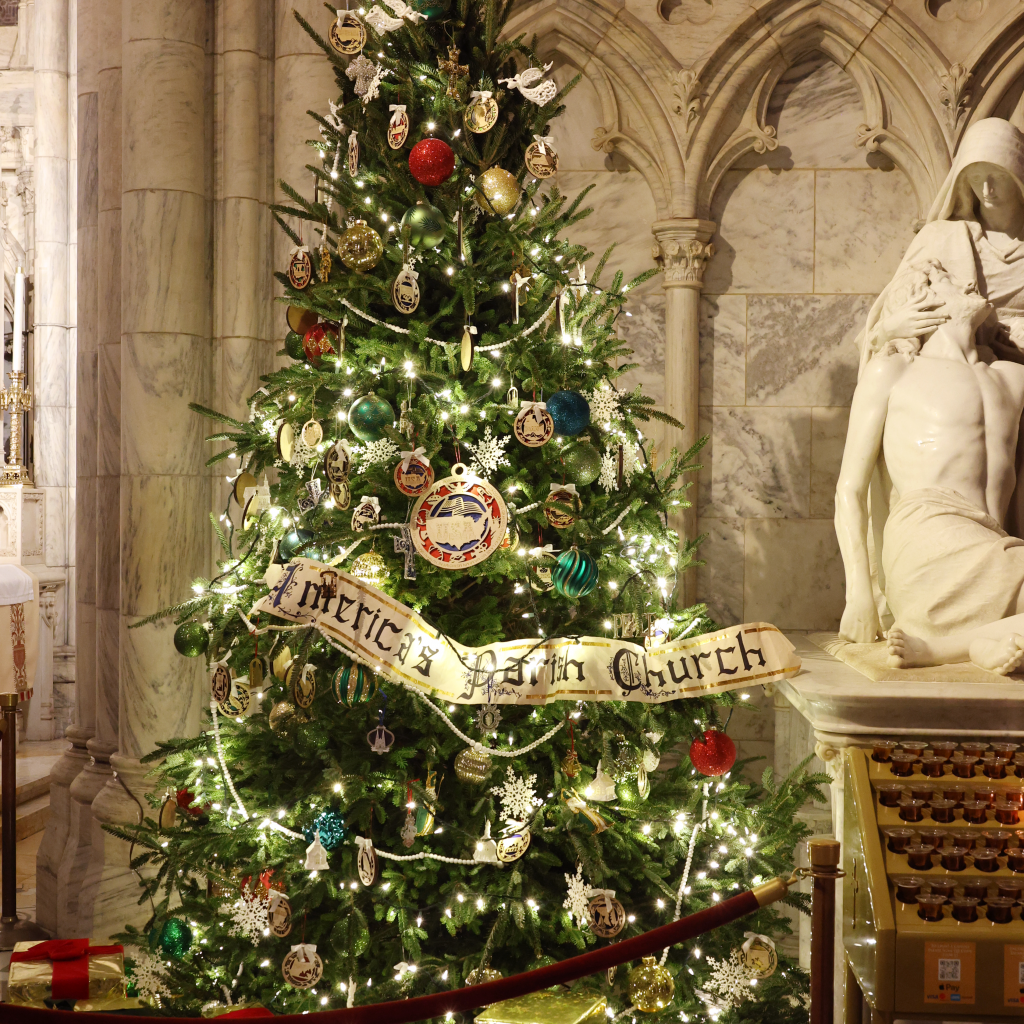 Gifts are scattered under the St. Patrick's Christmas tree adorned with a banner denoting its nickname as "America's Parish Church."