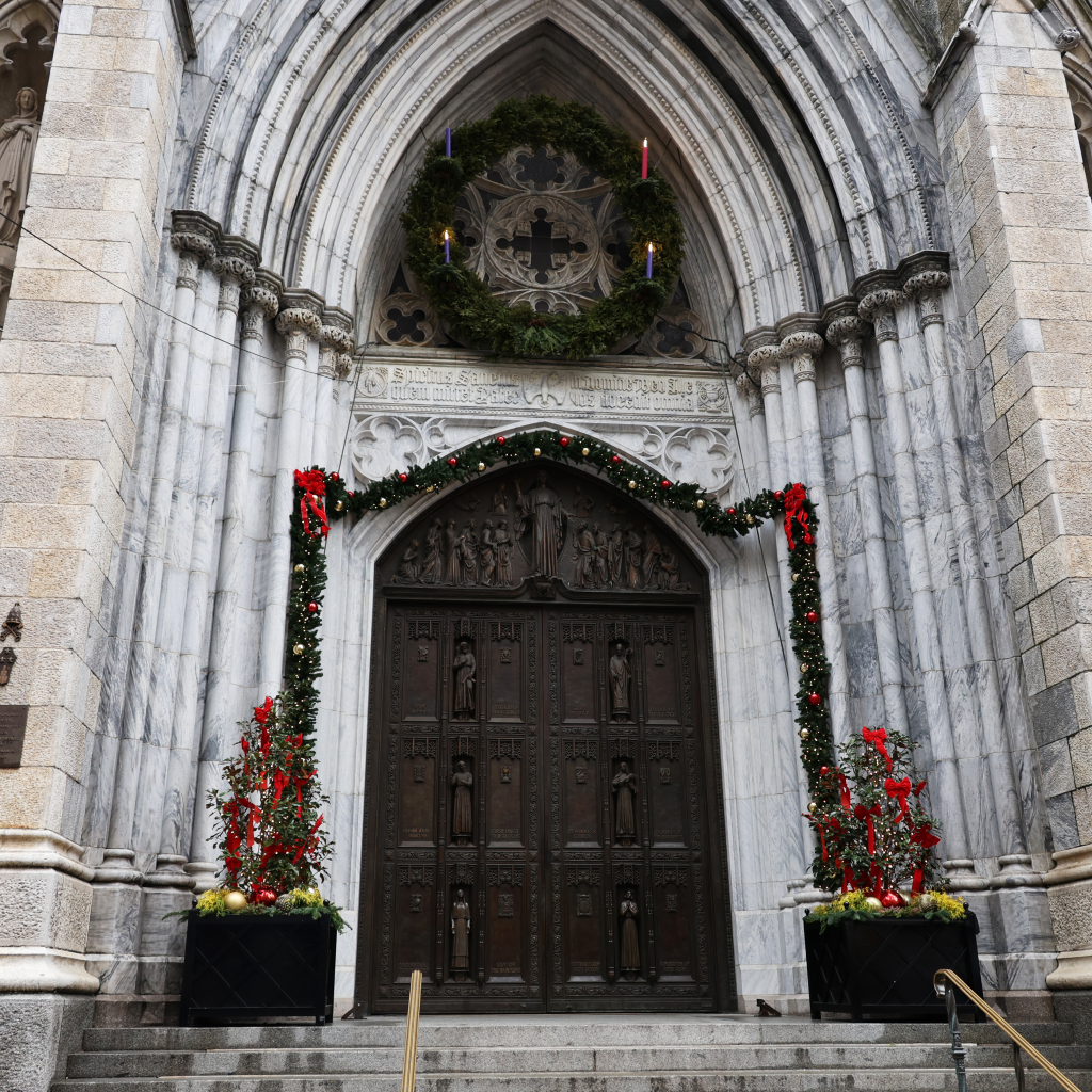 The massive doorway of St. Patrick's is decorated in garlands and red ribbons beneath a large Advent wreath.