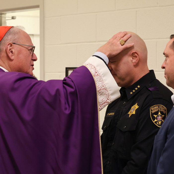 Cardinal Dolan adorns Sheriff Paul Arteta with ashes.