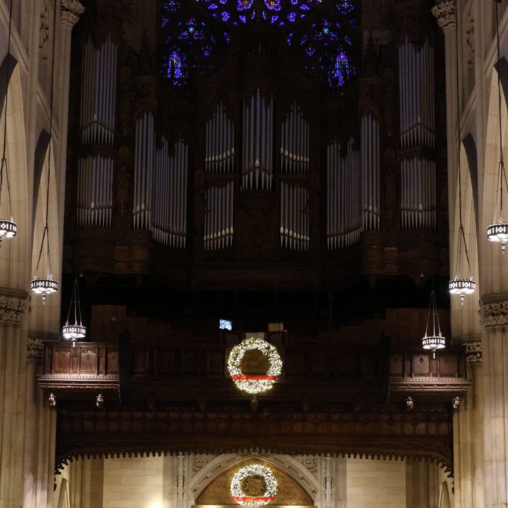 The lit- up wreaths by the entrance of the cathedral line up with the intricate circular stained glass of the front of St. Patrick's.